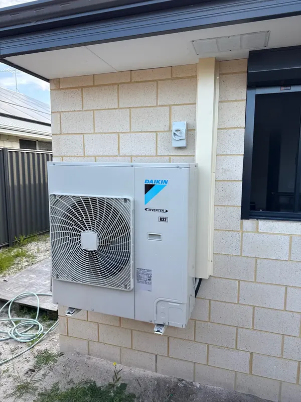 Daikin ducted air conditioning outdoor unit with its isolator on a brick wall, installed by OWCA Electrical