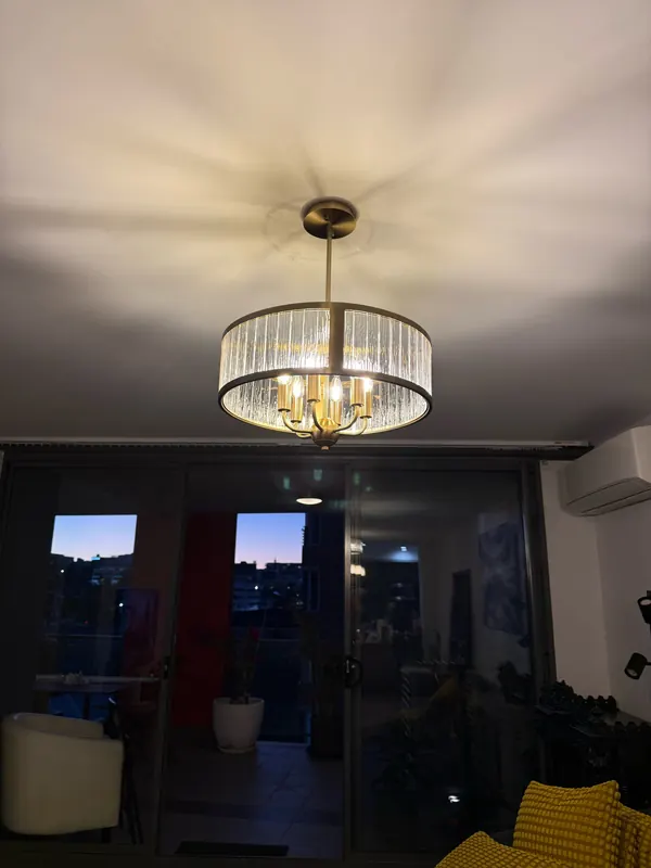 Crystal drum pendant light with gold frame lit up in an apartment living room, installed by OWCA Electrical